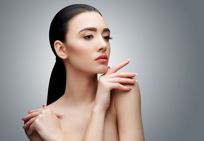 Woman with clear skin resting her hand on her shoulder