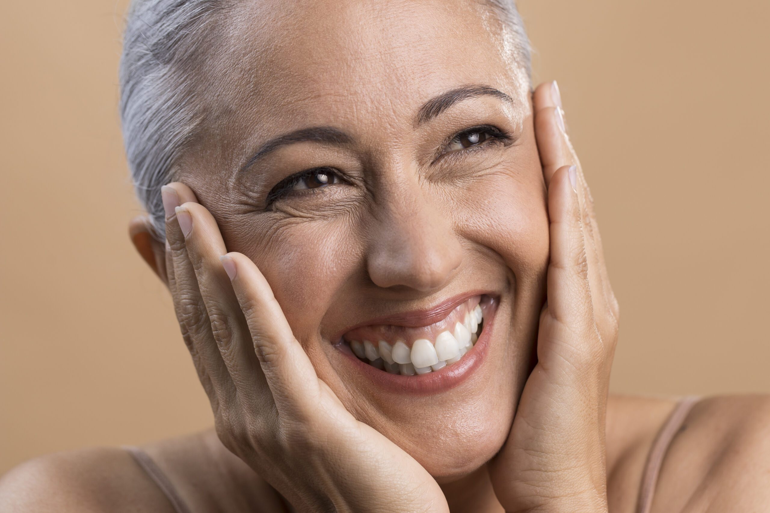 Smiling woman with her hands resting on her face
